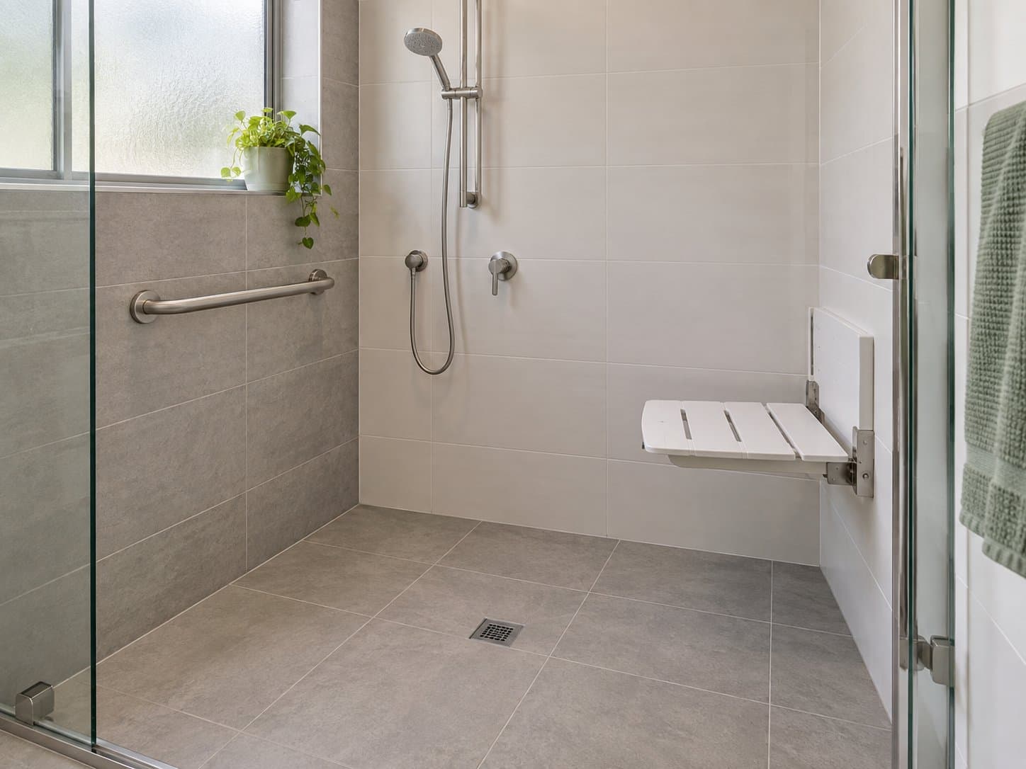 A residential bathroom with a level-entry shower, grab rail and non-slip flooring